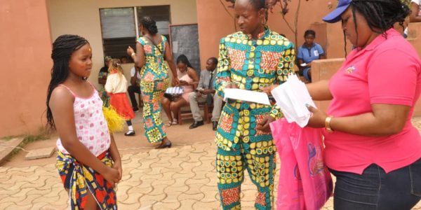 Une élève et des adultes pendant une remise de cadeaux